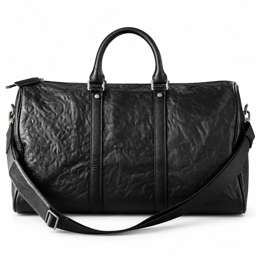 Textured black full-grain leather weekender bag with an adjustable shoulder strap draped across