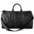 Textured black full-grain leather weekender bag with an adjustable shoulder strap draped across