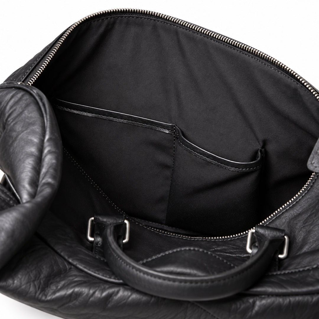 Textured black full-grain leather weekender bag interior with two leather-trimmed slip pockets