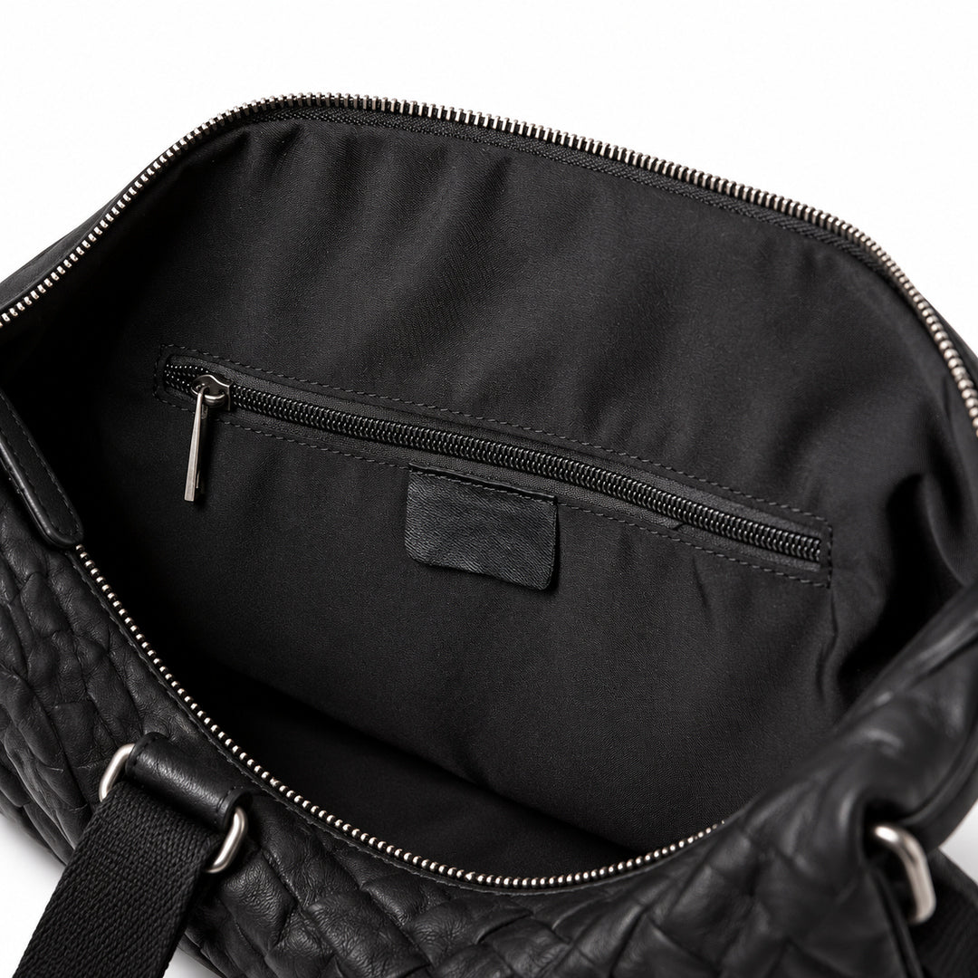 Textured black full-grain leather weekender bag interior with a zip pocket and black fabric lining