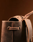 Close-up of the top handle and opening of a vintage brown leather backpack, showcasing Crazy Horse leather and stitching.