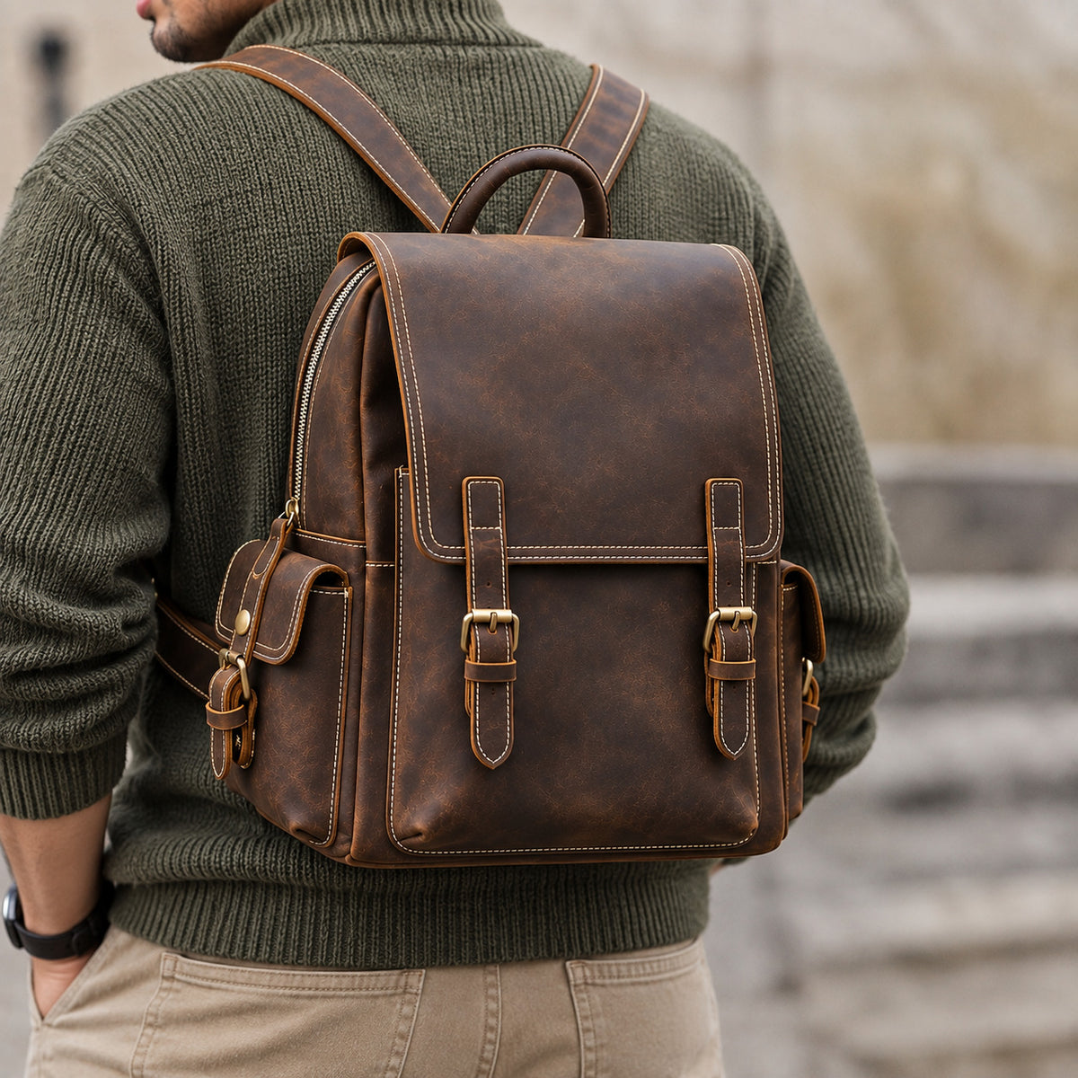 Vintage brown leather backpack for men with adjustable shoulder straps, buckle closure and side pockets, back view