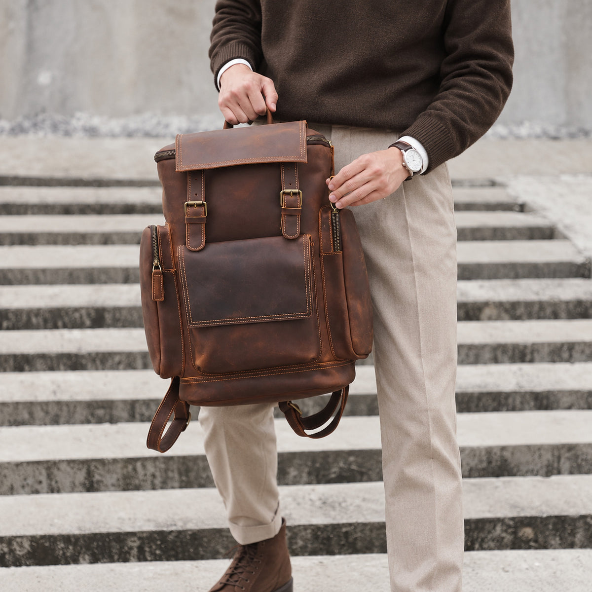 Vintage brown leather backpack for men with large front pocket, side zip pockets, buckle straps and carry handle, front view