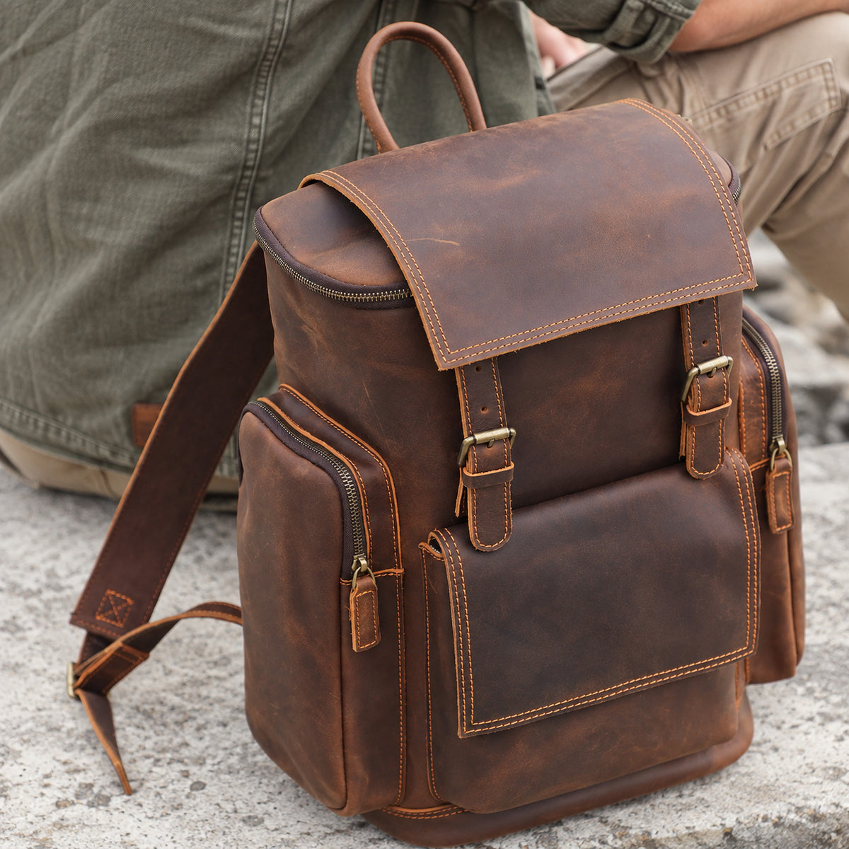 Vintage brown leather backpack for men with buckle closure, front pocket, zippered side pockets and top handle