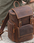 Vintage brown leather backpack for men with buckle closure, front pocket, zippered side pockets and top handle