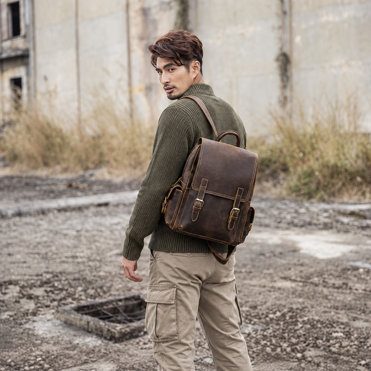 Vintage brown leather backpack for men with buckle straps and side pockets, worn as a travel rucksack outdoors