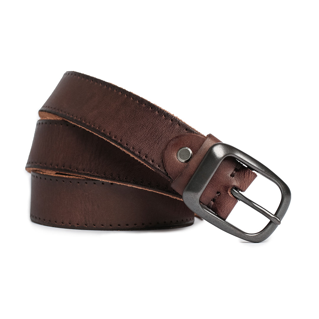 Close-up view of a vintage-style brown leather belt rolled up, highlighting its sturdy metal buckle and hand-stitched edges.