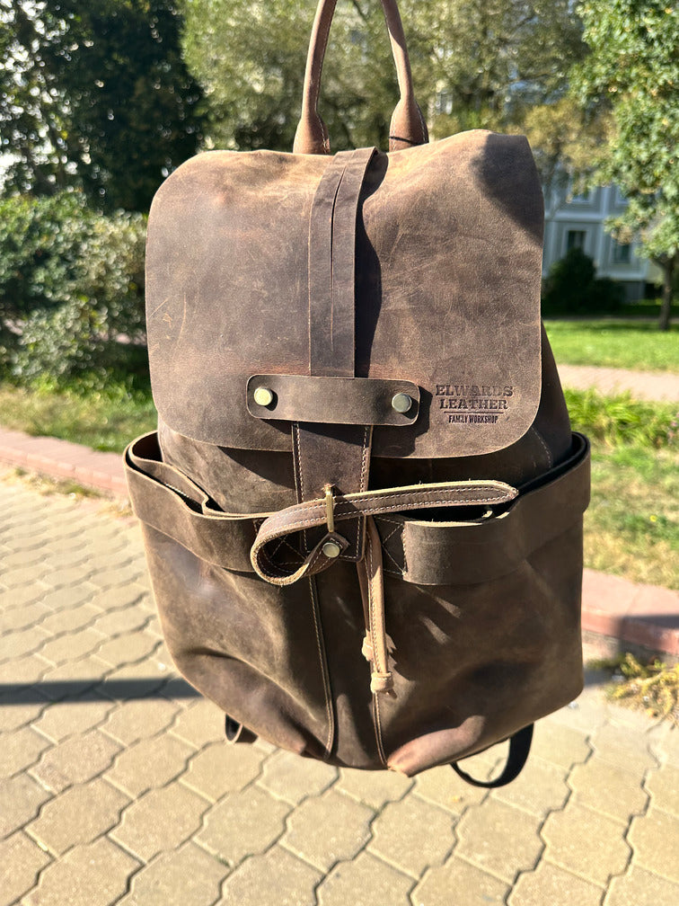Brown leather backpack hanging on a hook, highlighting the premium quality and vintage design.