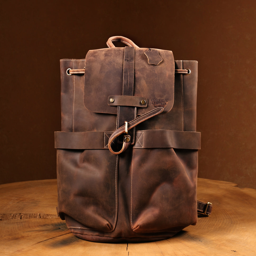 Brown Crazy Horse leather backpack on a wooden table, highlighting its vintage finish and detailed stitching.