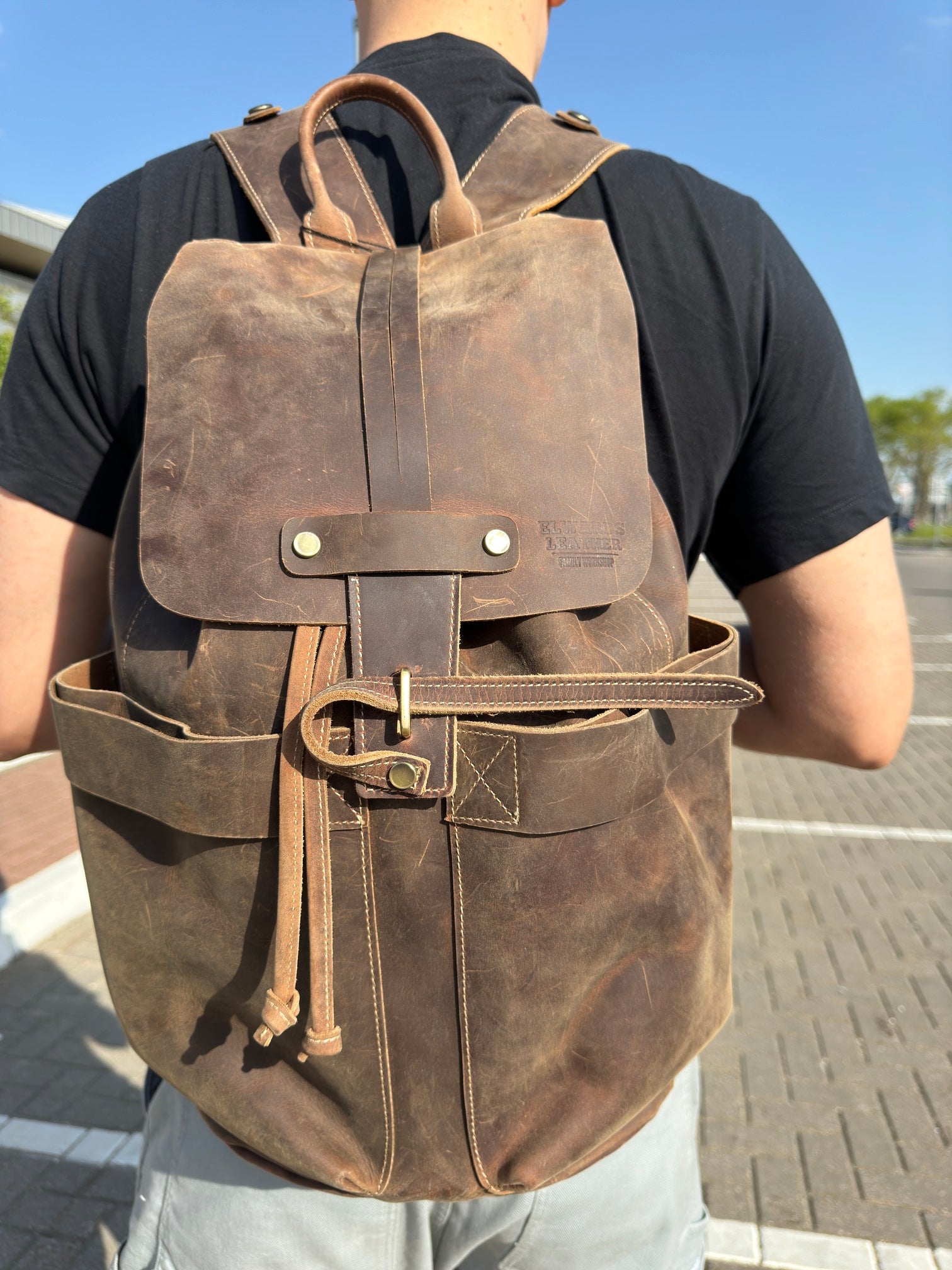 Brown leather backpack on a person’s back, featuring vintage design with adjustable straps for comfort.