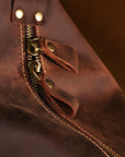 Close-up of high-quality brass zipper pull and stitching on vintage handmade leather travel duffle bag