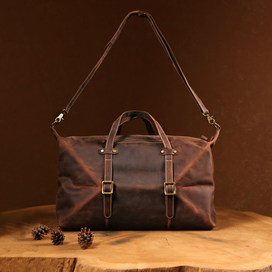 Front view of a vintage Crazy Horse leather duffle bag, handcrafted with adjustable strap and brass buckle details.